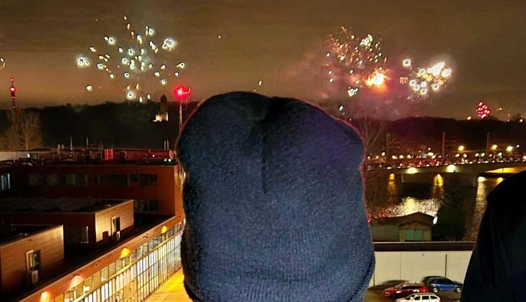 Ein Feuerwehrmann blickt auf ein Feuerwerk an Silvester. Ein Feuerwehrmann blickt auf ein Feuerwerk an Silvester.