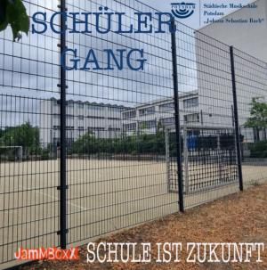 Durch einen umgitterten Pausen-Sportplatz schauen wir auf ein Schulzentrum.