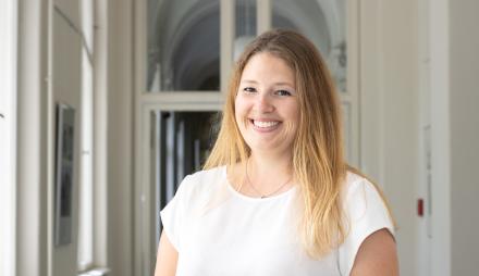 Sie sehen die Beauftragte für Migration und Integration Dr. Amanda Palenberg, welche in einem Lichtdurchfluteten Flur steht