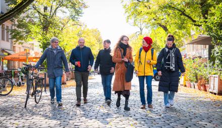Drei Männer und drei Frau laufen in der herbstlichen Dortustraße Richtung Kamera.