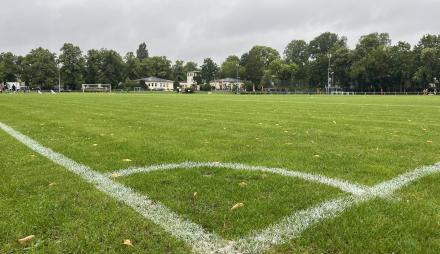 Die weißen Seitenlinien einer Ecke des Sportplatzes an der Berliner Straße sind zu sehen, im Hintergrund des Fußballplatzes steht das einstöckige Vereinsgebäude