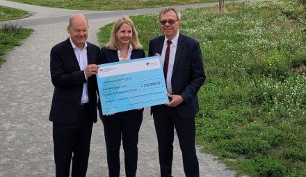 Bundestagsabgeordneter Olaf Scholz, Bundesbauministerin Verena Hubertz und Bürgermeister Burkhard Exner im Nuthepark bei der Übergabe von Fördermitteln.