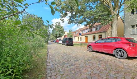 Auf einer Straße mit Pflastersteinen stehen zwei Autos.