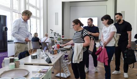 Mehrere Personen informieren sich auf Informationsmesse zur Verpackungssteuer am 27. Mai