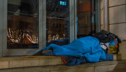 Eine Peron liegt mit Decken bedeckt und Taschen auf einer Treppe.