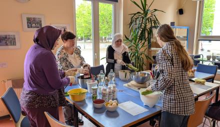 Vier Frauen bereiten an einem Tisch ein Gericht zu.