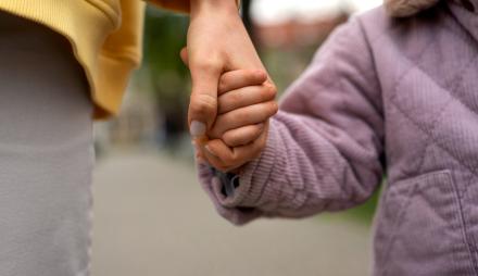 Kind und erwachsene Person Hand in Hand