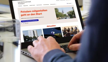 Notebook mit der Startseite von mitgestalten.potsdam.de, an dem eine Person arbeitet.