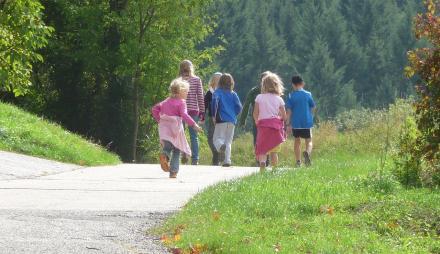 Eine Familie läuft auf einem Weg, der von grünen Flächen gerahmt ist