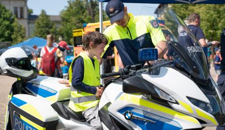 Ein Polizist erklärt einem Jungen die Motorräder der Polizei.