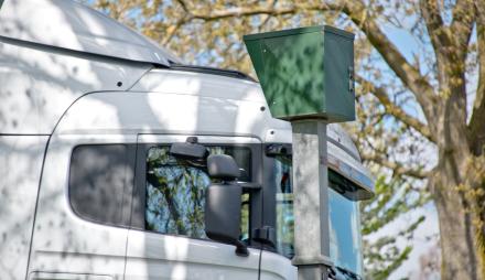 Ein Blitzer in einer Straße, an dem ein LKW vorbeifährt.