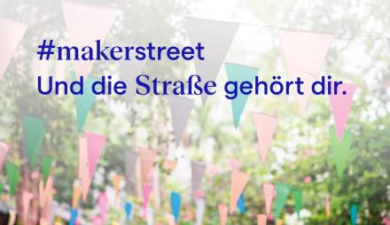 Schrift über Wimpeln, die in den Bäumen gespannt sind.