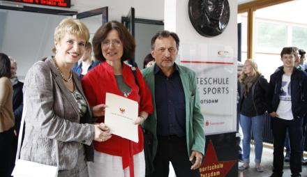 Die Beigeordnete für Bildung, Kultur und Sport, Dr. Iris Magdowski (M.), nimmt gemeinsam mit dem Leiter der Sportschule, Rüdiger Ziemer, den Fördermittelbescheid von Bildungsministerin Dr. Martina Münch entgegen.
