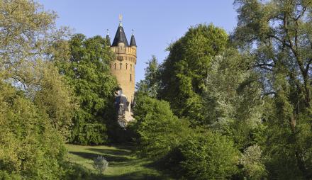 Das Bild zeigt den Flatowturm inmitten grüner Bäume im Park Babelsberg.
