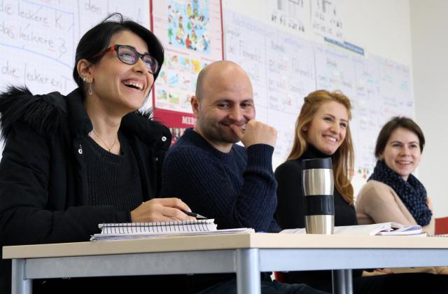 Das Foto zeigt vier an einem Tisch sitzende Personen mit Arbeitsunterlagen.