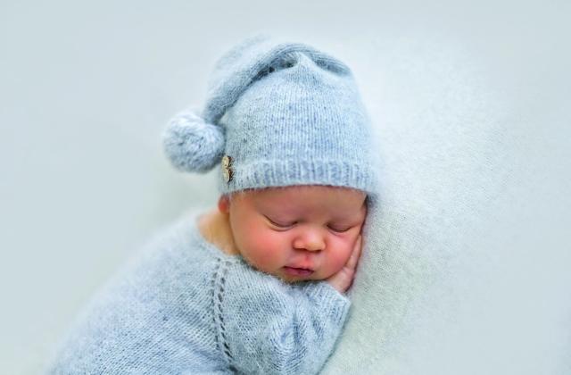 Schlafendes Baby Das Foto zeigt ein schlafendes Baby in blauem Strampelanzug mit blauer Zipfelmütze.