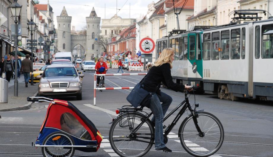Fahrradfahrer in Potsdam mit Tram und Nauener Tor im Hintergrund