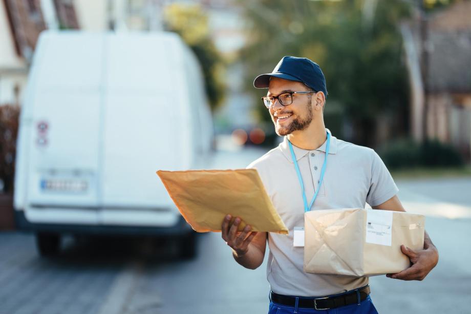 Lächelnder Postbote mit Paketen in der Hand