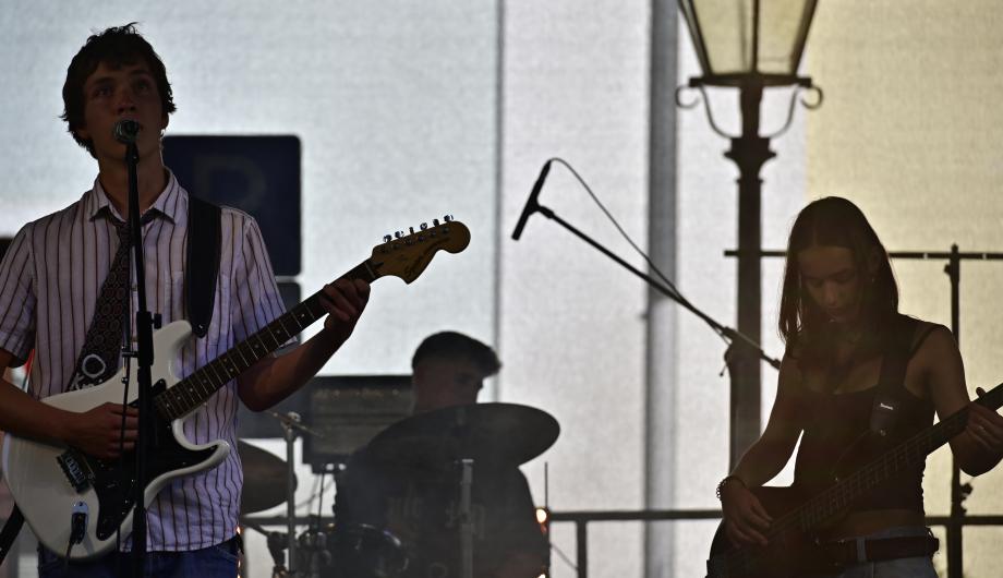 Ein Indie-Trio performed auf einer Bühne. Das Bild wirkt etwas geheimnisvoll und gemalt.