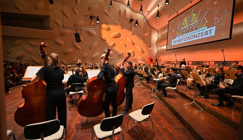 Einstimmen auf einen großen Abend Wir schauen von hinten durch die Gruppe der Kontrabasses*innen auf Orchester und Publikum