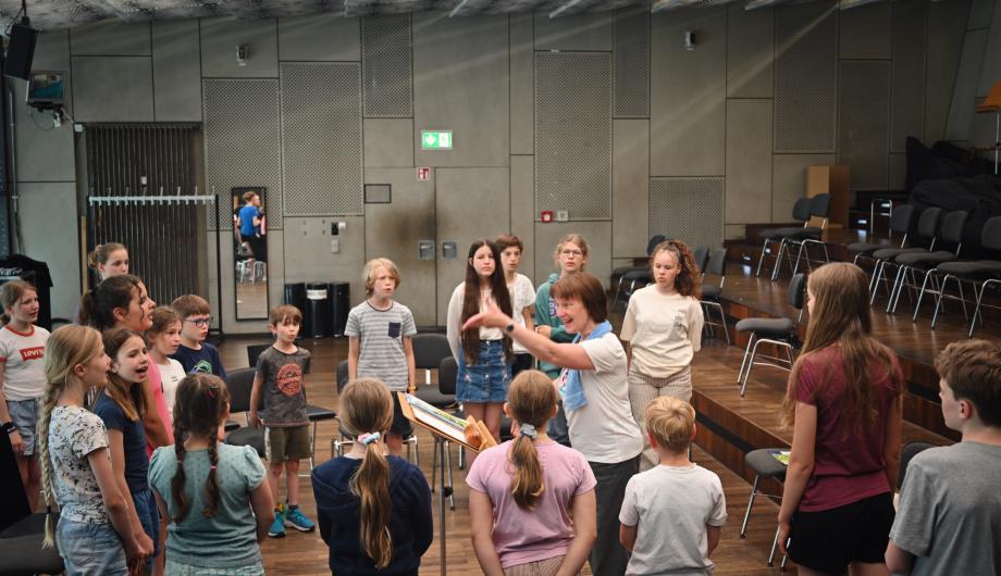 Probearbeit mit La Corista In der Probebühne des Nikolaisaal leitet eine engagierte Chorleiterin Übungen für den umstehenden Kinderchor an