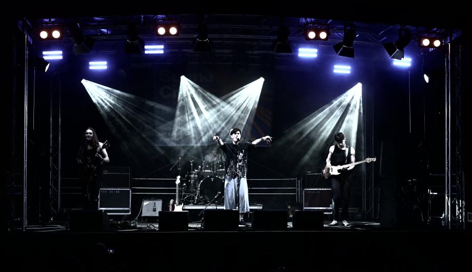 Eine Rockband mit 4 jungen Männern performed auf dramatisch beleuchteter Bühne