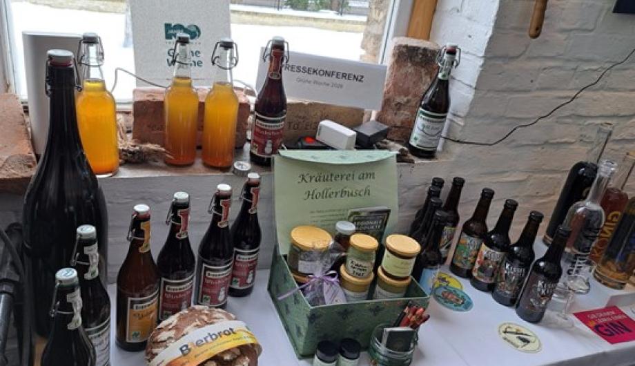 Auf einem Tisch sind Produkte aus Potsdam zu sehen, die auf der Messe Grüne Woche Berlin präsentirt werden (u.a Flaschen mit Apfelsaft und Gin, Brot)