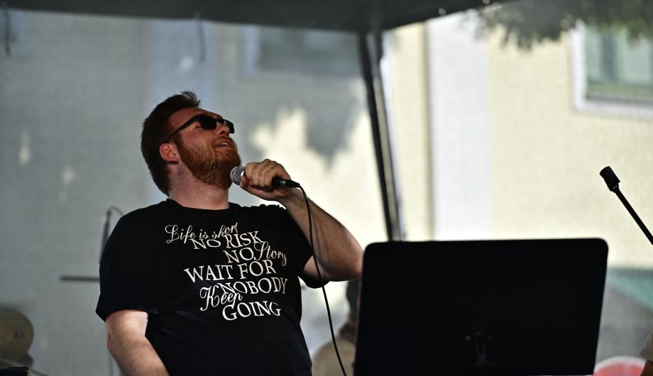 Ein Rocksänger auf der Bühne in voller Aktion - sein T-Shirt sagt unter anderem: No Risk No Story