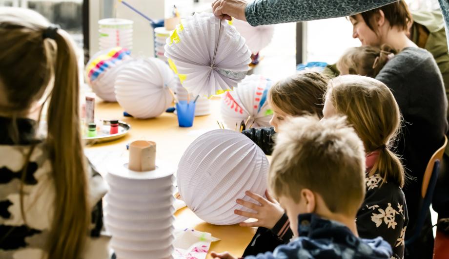 Mehrere Kinder basteln Laternen aus Papier.