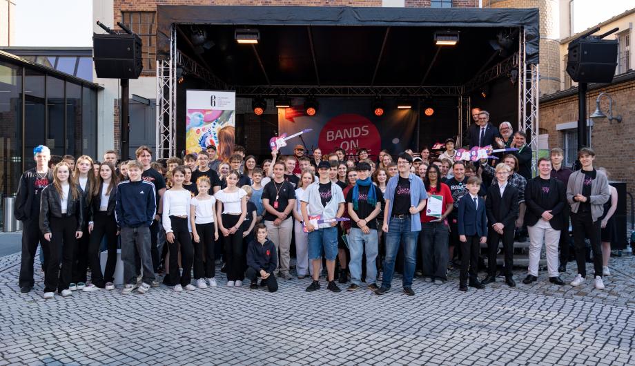 Abschlussfoto: Sehr viele jugendliche Musikerinnen und Musiker stehen zufrieden vor der Bühne des Bandcontest.