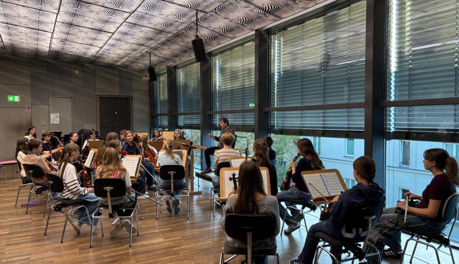 Das gemischte Jugendorchester STRINGendo probt auf der Probebühne im Nikolaisaal. Der Fussboden ist hölzern und durch Jalousien fällt eine strukturiertes Licht
