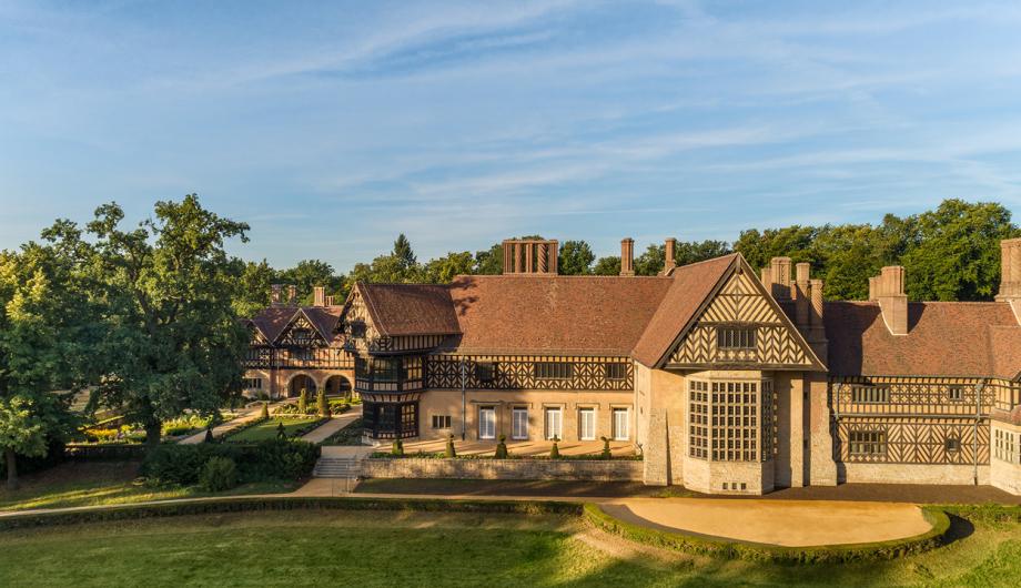 Schloss Cecilienhof im Neuen Garten Auf dem Foto ist im Sonnenlicht das Schloss Cecilienhof im Neuen Garten unter strahlend blauem Himmel zu sehen.