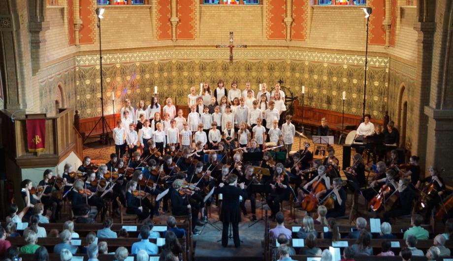 Konzert 2019: Kinderchor und Orchester STRINGendo - Erlöserkirche Das Bild zeigt den Großen Chor, ein Orchester und Publikum bei einem Kirchenkonzert.