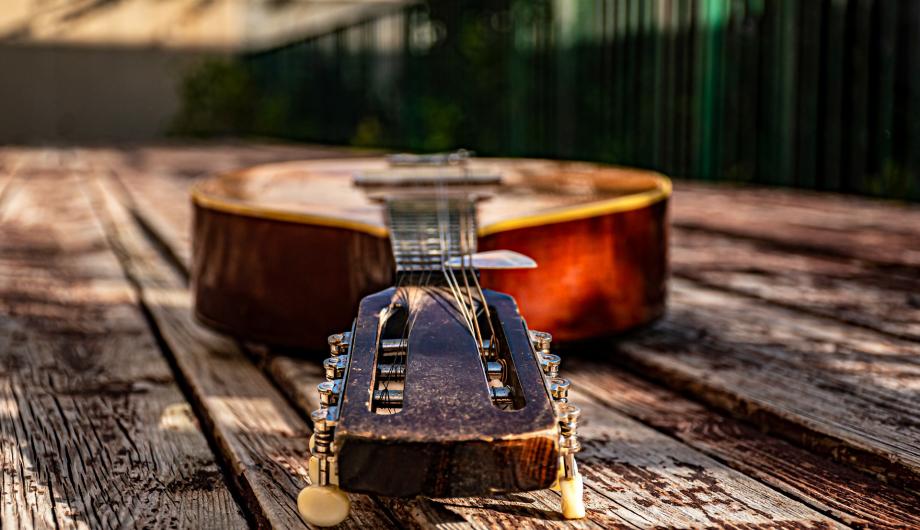 Eine Mandoline liegt auf einem Holztisch im Freien. Es gibt ein schönes Licht-Schattenspiel.