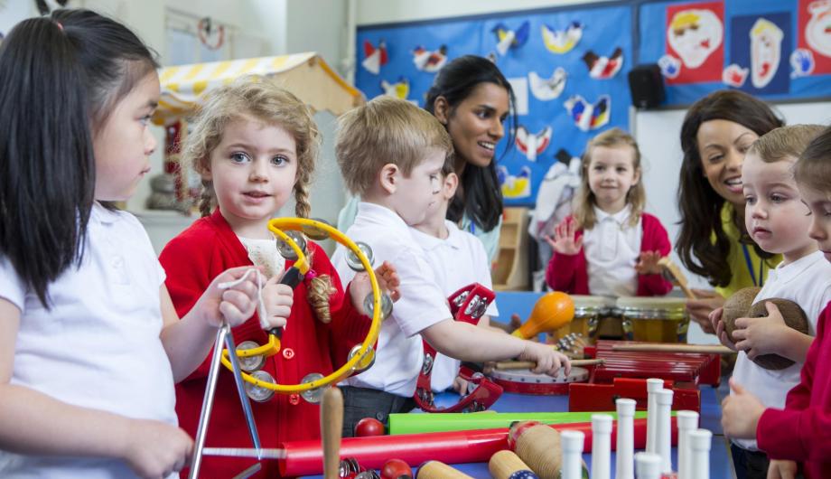 Kinder an einem Tisch - reich gedeckt mit einfachen Musikinstrumenten - zum Beispiel Rasseln und Trommeln