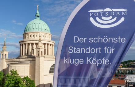 Blaue Beachflag mit Aufschrift "der schönste Standort für kluge Köpfe" vor der Nikolaikirche