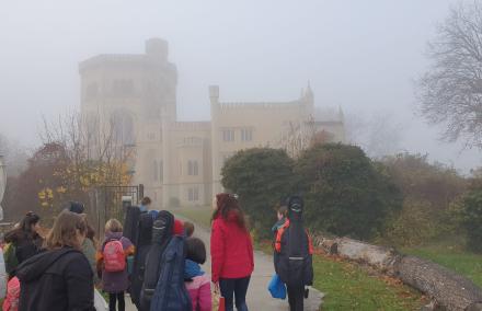 Eine gGruppe von jungen Orchestermitgliedern geht im Nebel auf ein Schloss zu