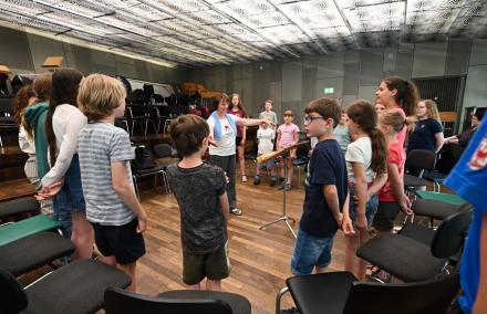Probearbeit bei La Corista Blick in einen Kinderchorkreis - in der Mitte breitet Marion Kuchenbecker ihre Arme aus und leitet Ihre Kinder an.