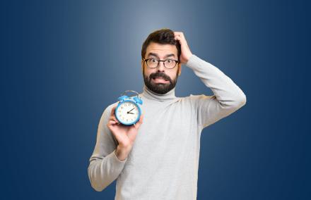 Keine Zeit aufs Amt zu kommen? Ein Mann unter Zeitdruck hält einen Wecker in der Hand.