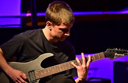 Ein junger E-Gitarrist spreizt seine Finger beim Vorspiel über das Gitarrengriffbrett