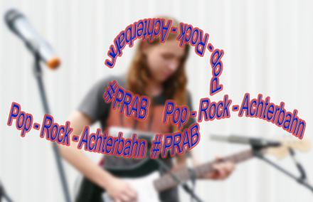 DIe Worte Pop-Rock-Achterbahn #PRAB reihen und ringeln sich wie eine Achterbahn - im Hintergrund ist ein Gitarrist zu sehen