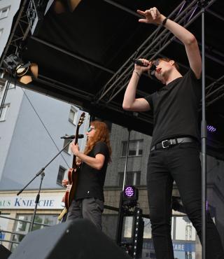 Auf einer Bühne sehen wir einen jungen Rocksänger in voller Aktion