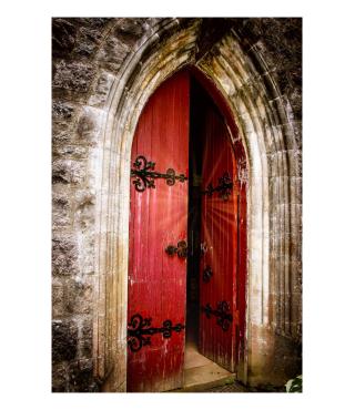 Aus einer geöffneten, hölzernen Kirchentüre strömen warme Lichtstrahlen