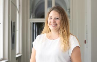 Sie sehen die Beauftragte für Migration und Integration Dr. Amanda Palenberg, welche in einem Lichtdurchfluteten Flur steht