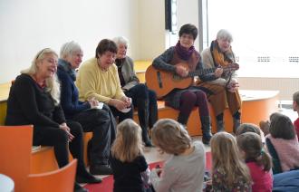 Lesepatinnen und Lesepaten lesen und spielen Kindern in der Stadt- und Landesbibliothek vor.