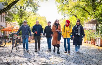 Drei Männer und drei Frau laufen in der herbstlichen Dortustraße Richtung Kamera.