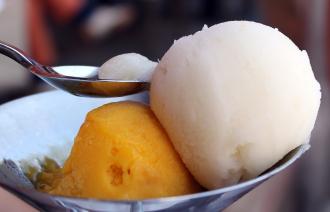 Zwei Kugeln Eis in oranger und weißer Farbe in einem Schüssel.