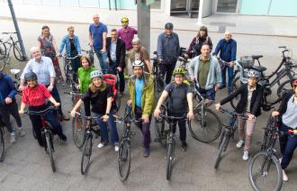 Mehrere Personen auf Fahrrädern vor dem Verwaltungsstandort Edisonallee schauen in die Kamera zum Auftakt von STADTRADELN 2025. 