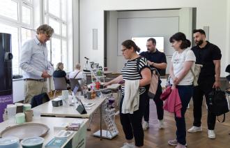 Mehrere Personen informieren sich auf Informationsmesse zur Verpackungssteuer am 27. Mai