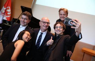 Ministerpräsident Woidke ist bei einem fröhlichen Selfie-Shoot mit Jugendlichen zu sehen.